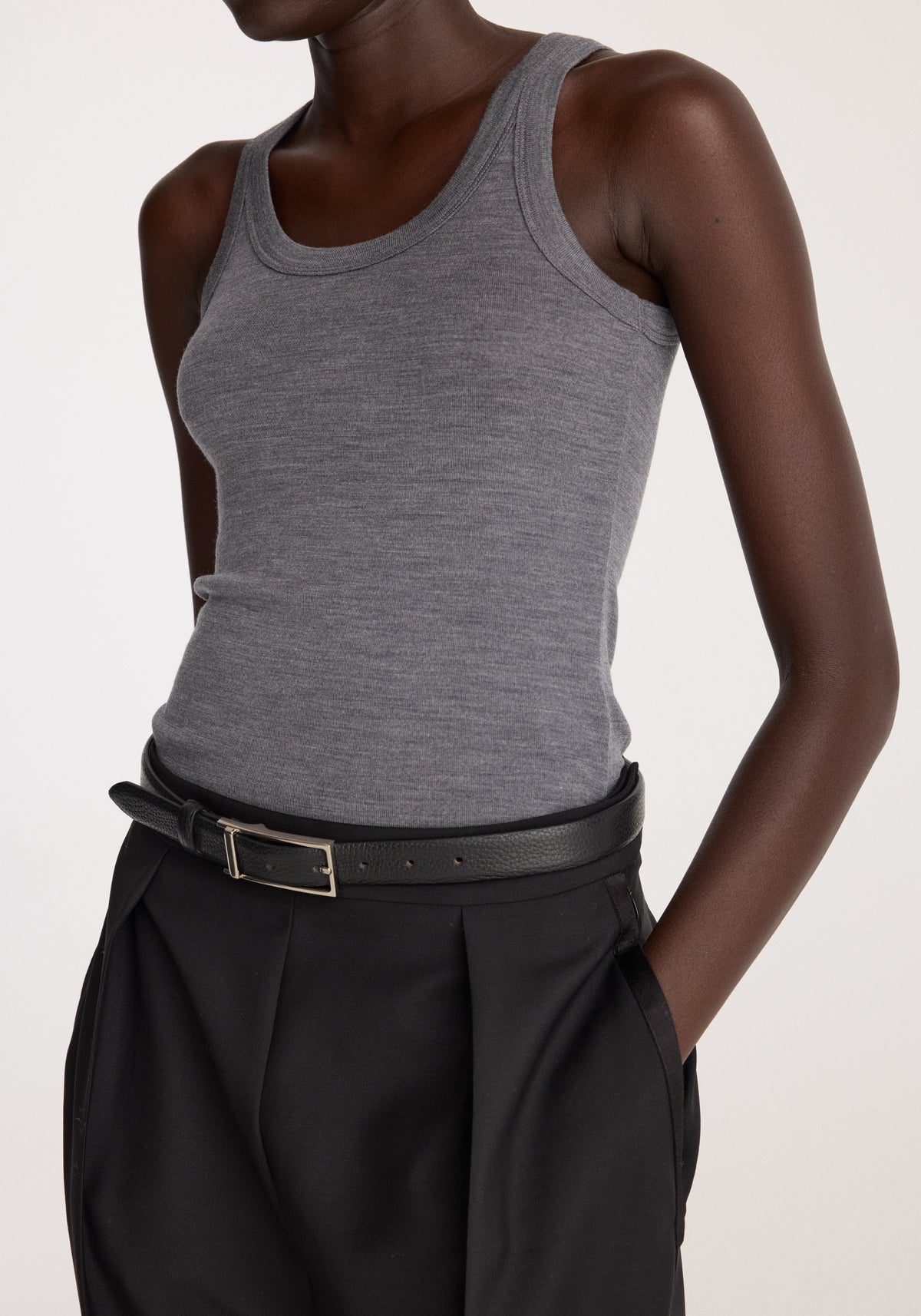 Merino scoop neck top | mid grey melange on a model styled with black pleated trousers and a black belt