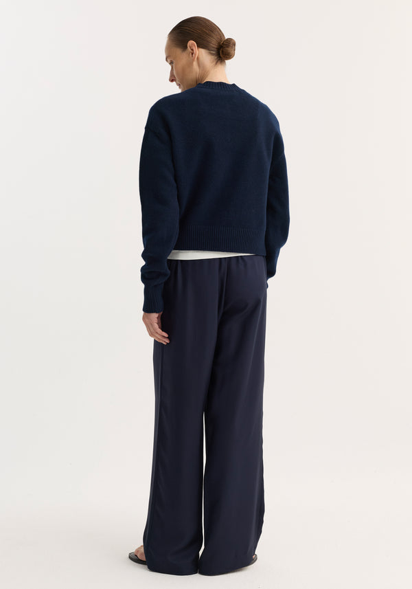 Person wearing a Short boiled cardigan | navy, showcasing the cropped button-up design, high crew neck, and drop shoulders with a soft, structured texture.