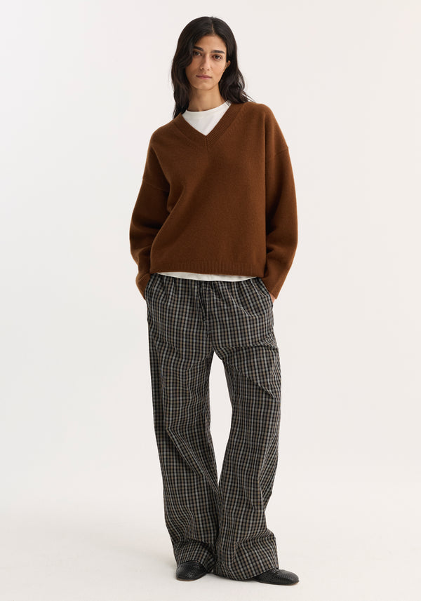 Model wearing Relaxed fit trousers in black/brown check pattern, featuring a wide-leg, drawstring waistband, and side seam pockets, styled with a brown sweater and loafers.
