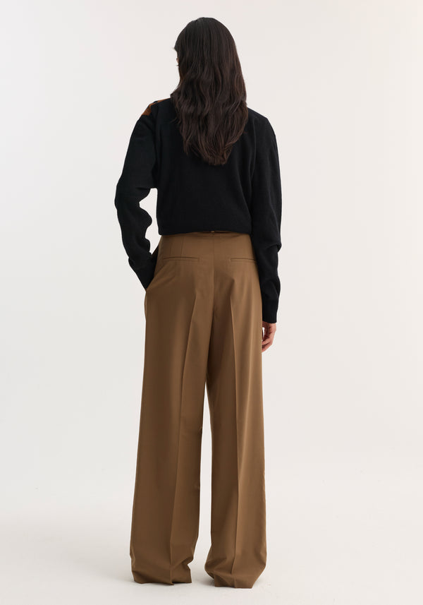Back view of a model wearing Mid-waist tailored trousers in mocha, featuring a structured waistband, wide-leg cut, and double pleats, paired with a black top.