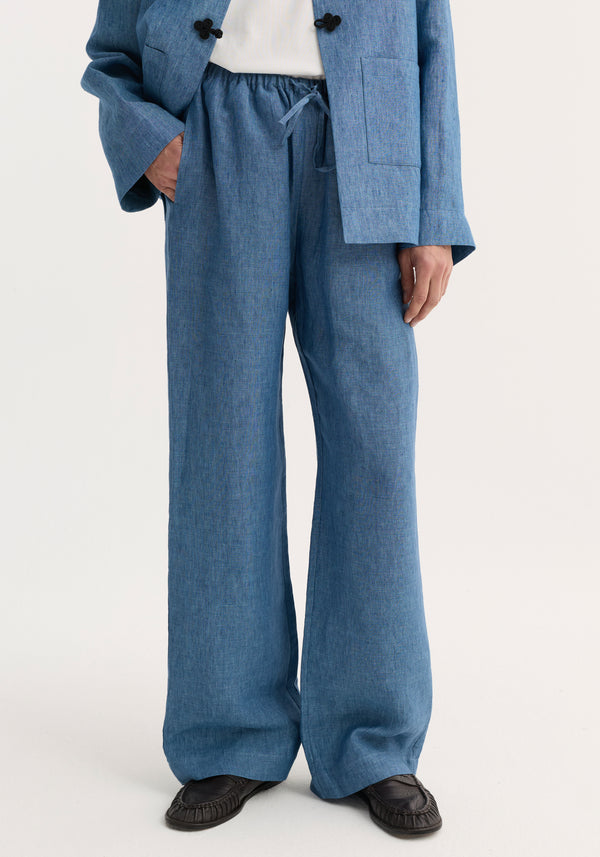 Person wears Relaxed fit trousers | ocean blue: wide-leg, drawstring waist, linen trousers with side pockets, styled with matching jacket and black moccasin loafers.