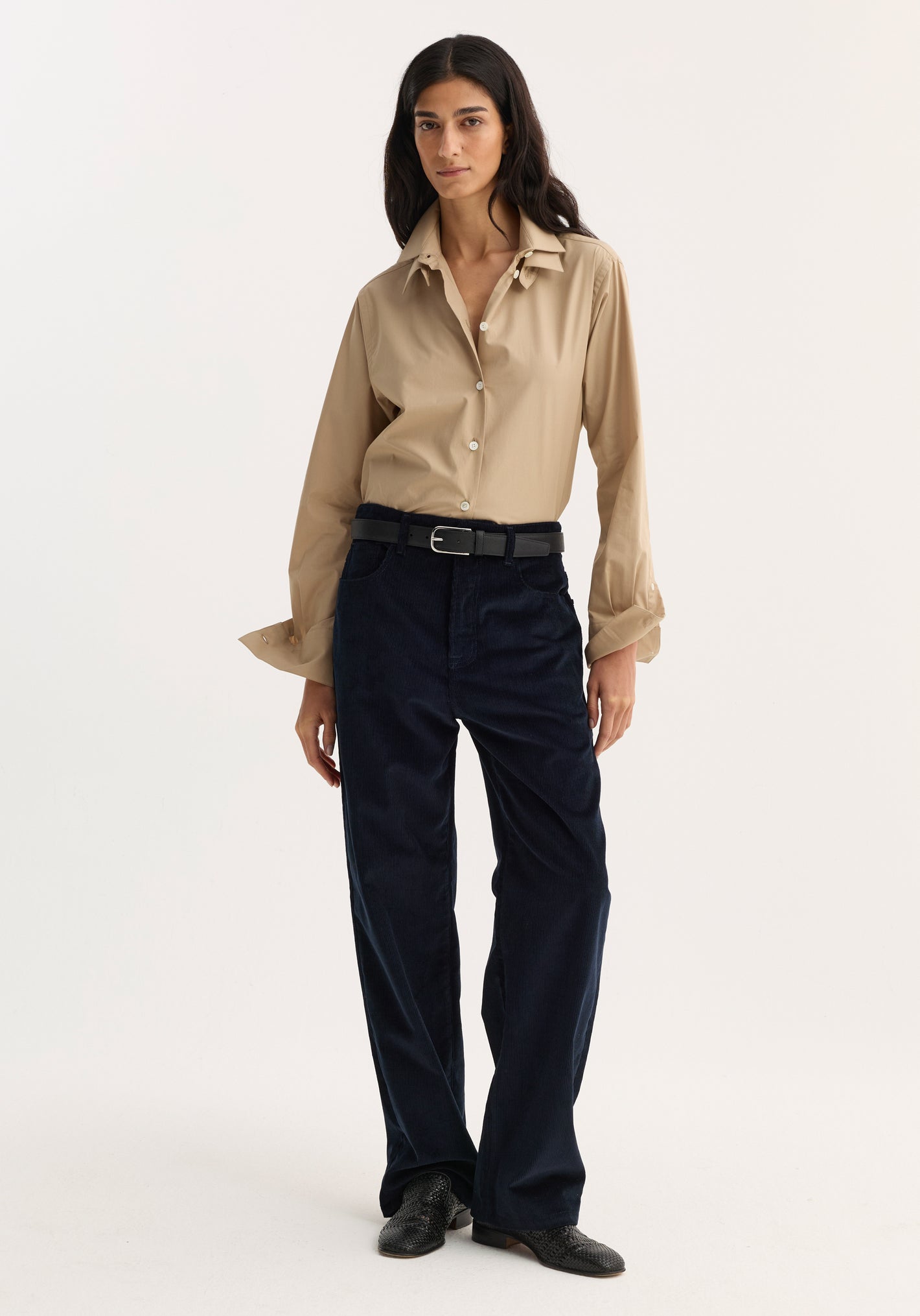 Model wearing Relaxed corduroy trousers | night, featuring a loose fit and denim-style details, paired with a beige button-up shirt and black textured shoes.