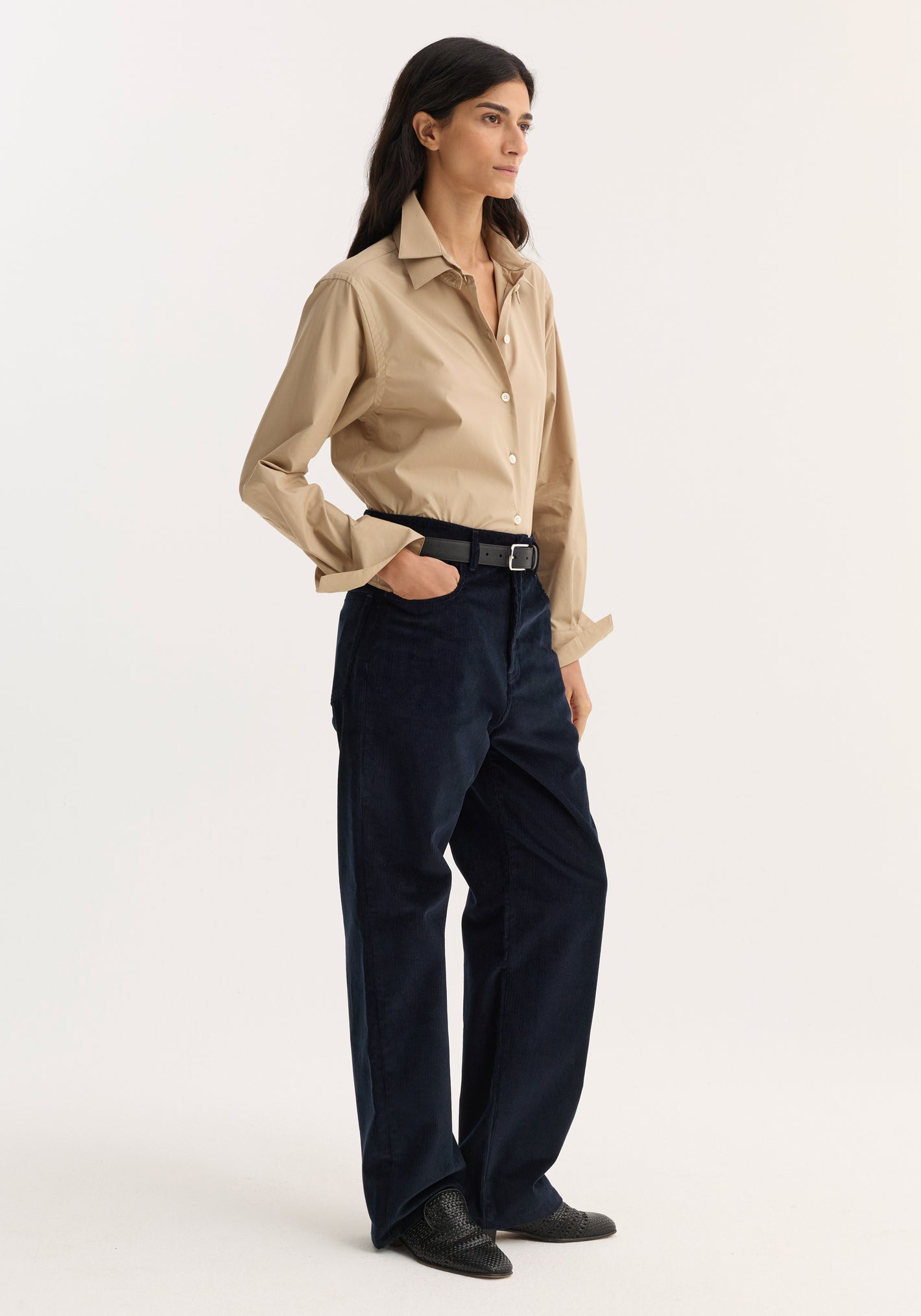Model wearing Relaxed corduroy trousers | night, navy hue, low-rise, loose leg, denim-style details, paired with a beige shirt and black woven loafers.