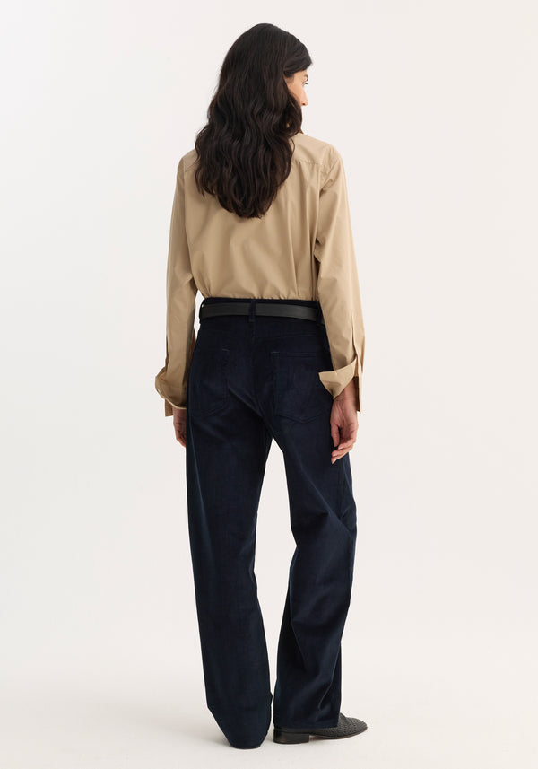 Person wearing Relaxed corduroy trousers | night, featuring wide-leg, low-rise fit, and denim-style details, paired with a light tan shirt and black belt.