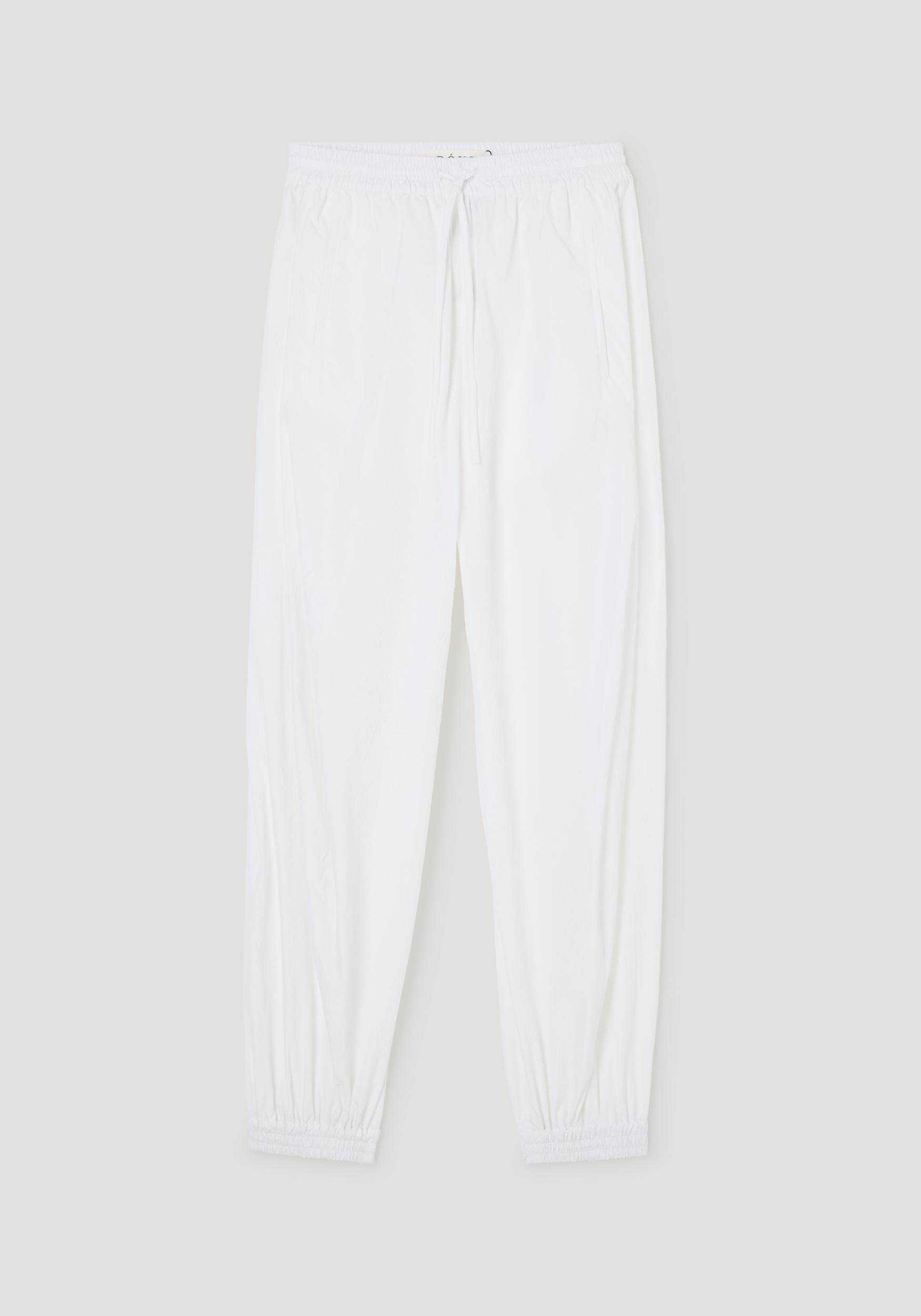 Balloon track pants in optic white with crinkled texture, featuring an elastic waistband, drawstring, welt pockets, and elastic cuffs for a voluminous look.