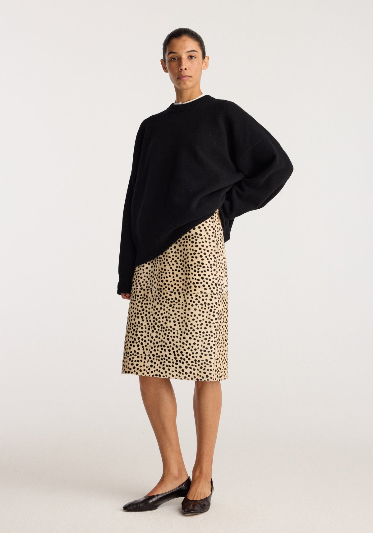 Pony hair pencil skirt | cheetah worn with a black oversized sweater and black flat shoes in a studio setting