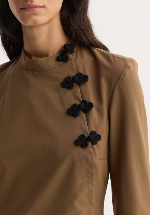 Pankou closure dress | mocha: Close-up of a camel-brown blouse or jacket with distinctive black pankou closures spiraling down from a high neckline.