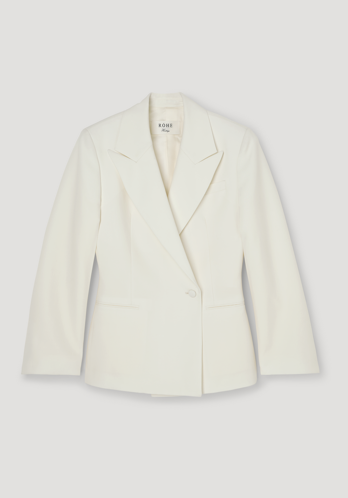 Hourglass shaped blazer in off white with peaked lapels, single button closure, structured silhouette, and slit pockets, by RÖHE Vintage. Made from 100% wool.