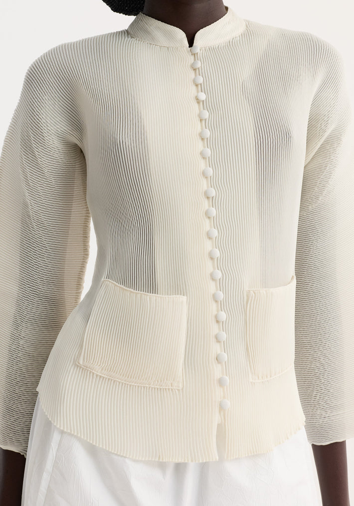 Model wears a Plissé cardigan | cream, featuring a mandarin collar, fabric-covered buttons, micro-pleated texture, and patch pockets, paired with a white bottom.