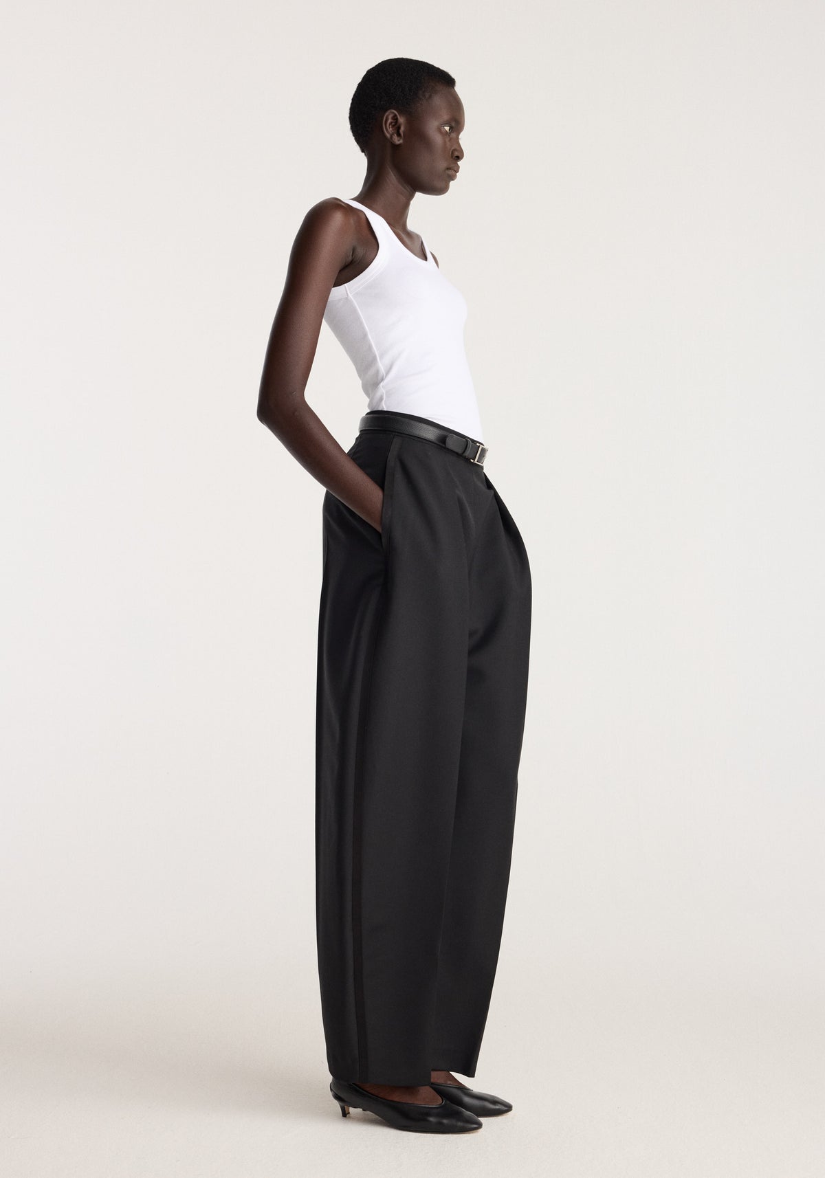 Scoop knitted top | optic white worn by a model with black wide leg trousers in a minimalist studio setting