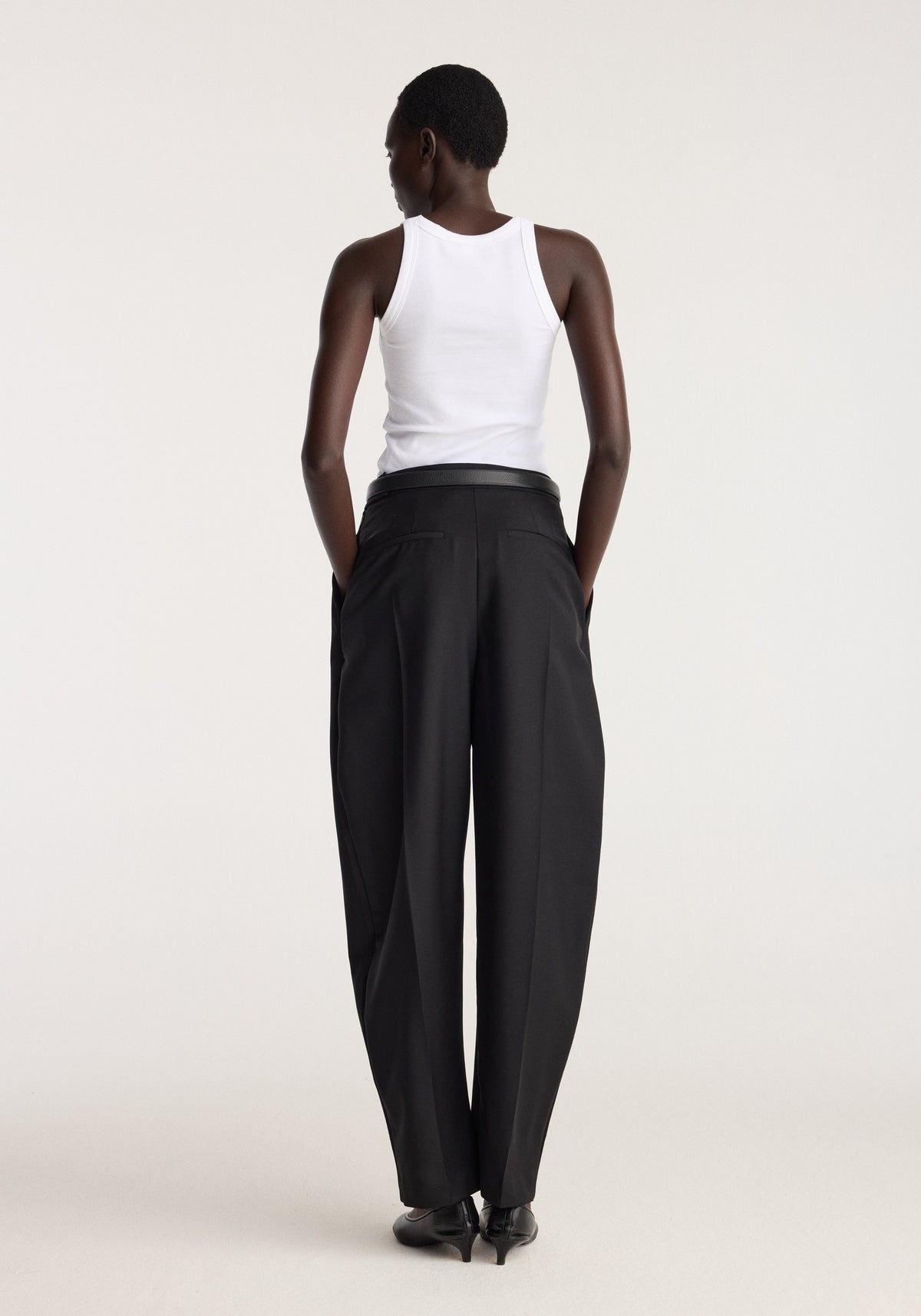 Scoop knitted top | optic white shown from the back on a model, featuring a sleeveless scoop neckline and fitted silhouette styled with black trousers