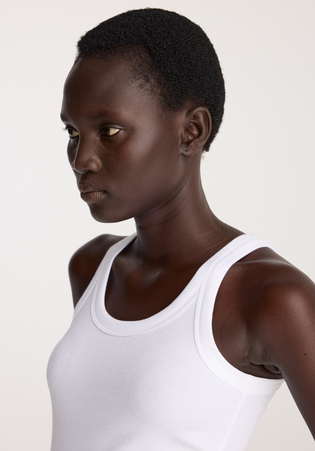 Scoop knitted top | optic white worn by a model featuring a sleeveless design and wide scoop neckline in soft white knit fabric
