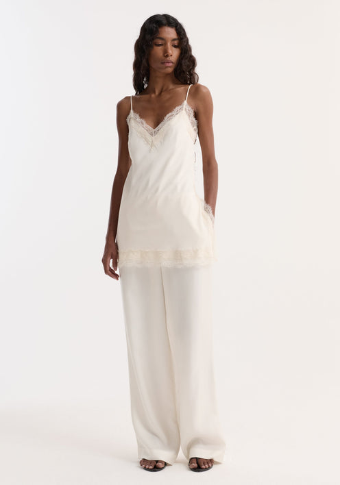 Model wearing Lace camisole | off white with lace-trimmed V-neck, adjustable straps, wide-leg trousers, and black sandals, highlighting a fluid, elegant silhouette.