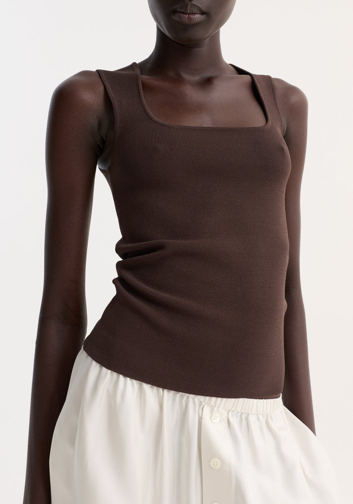 Bustier shaped knitted top in dark chocolate with a fitted silhouette and square neckline, paired with a high-waisted white skirt featuring button details.