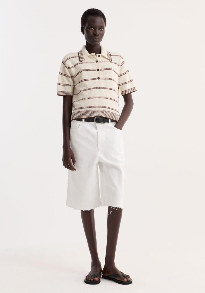 Model wearing Towelling striped polo in cream/brown with a cropped fit, paired with high-waisted white bermuda shorts and black sandals, exuding minimalistic style.