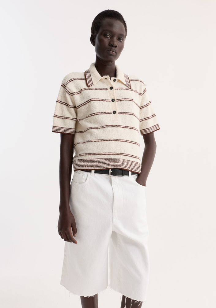 Model wearing Towelling striped polo in cream/brown with a cropped fit, paired with high-waisted white bermuda shorts and black sandals, exuding minimalistic style.
