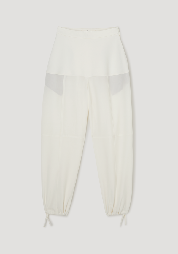 Architectural trousers in off-white featuring a skirt-style panel at the waist, seam detailing, and drawstring cuffs for a ballooned silhouette, crafted from 100% virgin wool.
