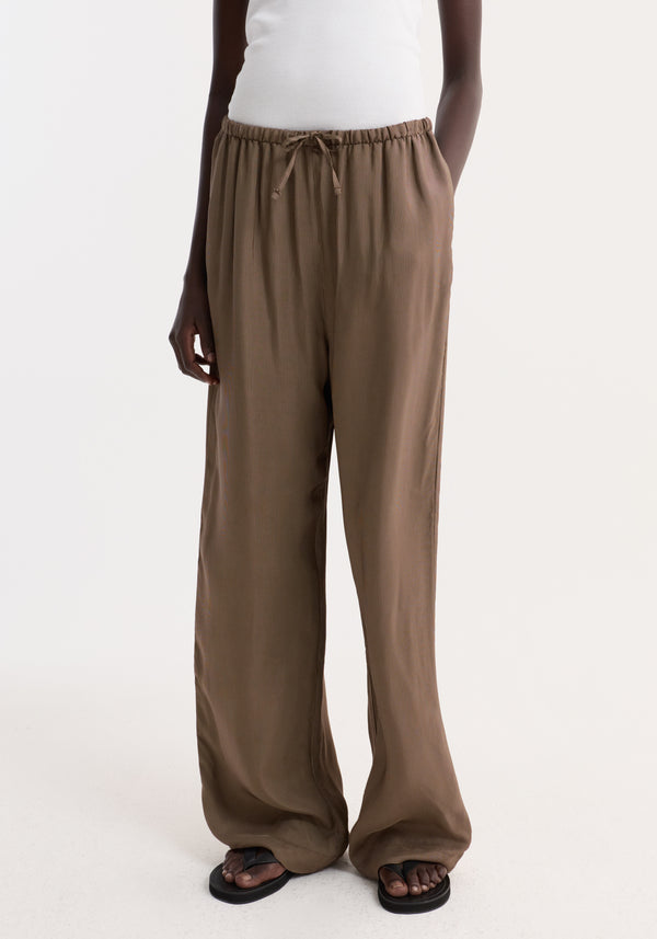 Person wearing Relaxed fit trousers | brown mini check with wide legs and a drawstring waistband, styled with side pockets and black flip-flop sandals.