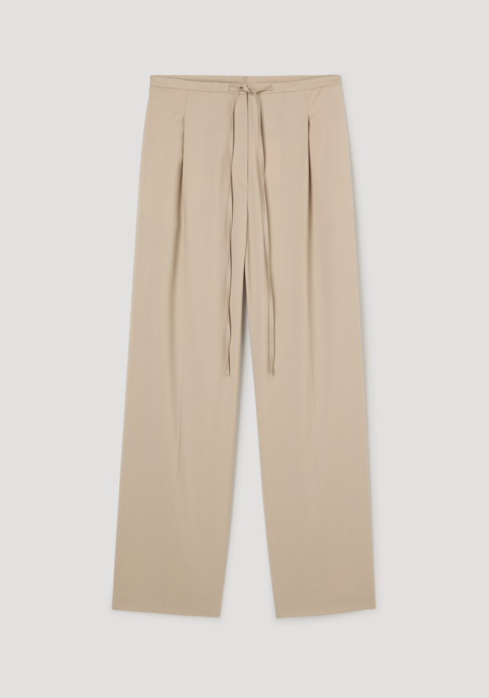 Relaxed drawstring trousers in light beige, featuring a wide-leg design and drawstring waistband, crafted from 100% virgin wool for comfort and elegance.