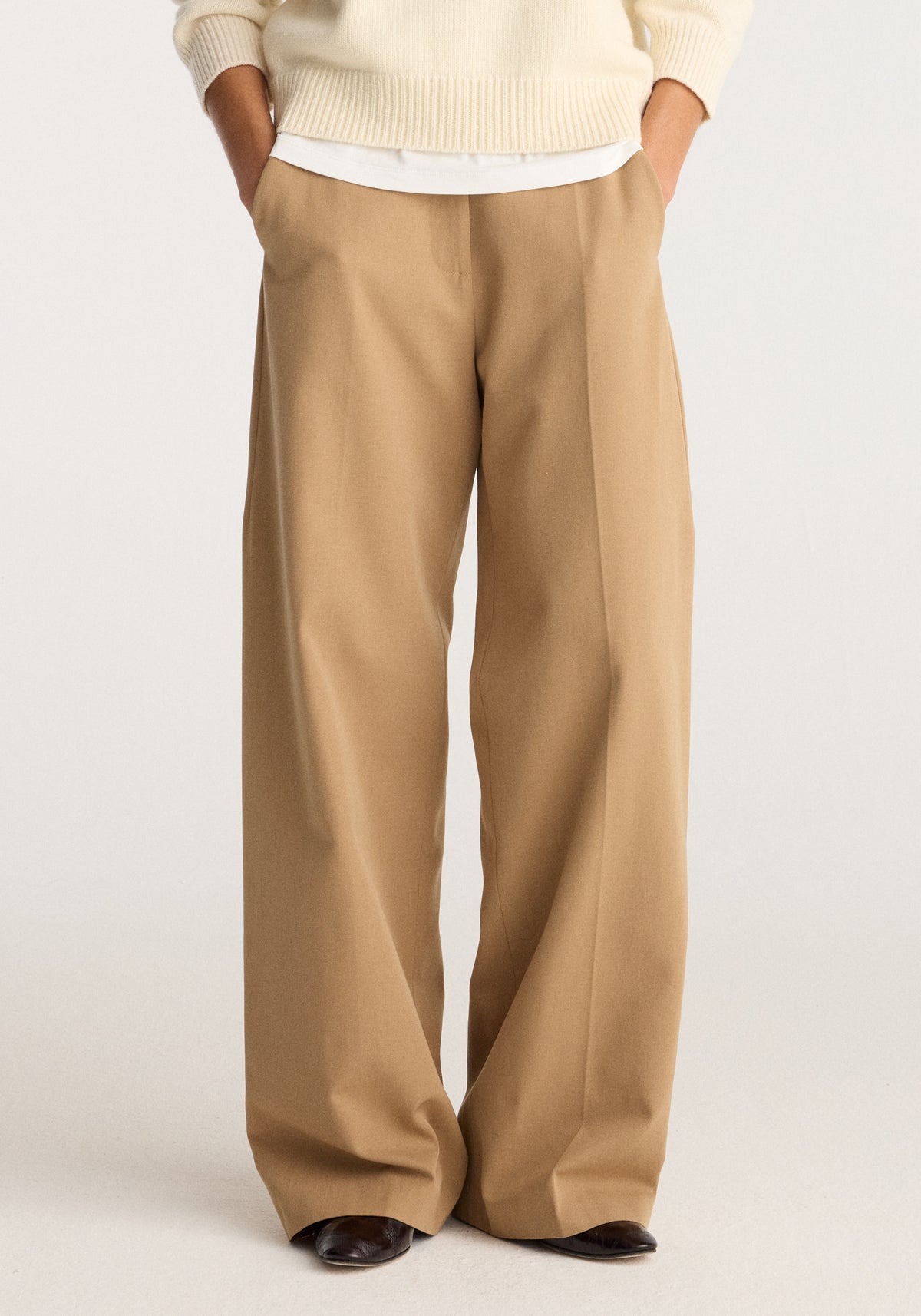 Classic loose fit chino | beige shown on a model with a relaxed wide leg, front pleats, and hands in pockets, styled with a cream sweater and dark loafers
