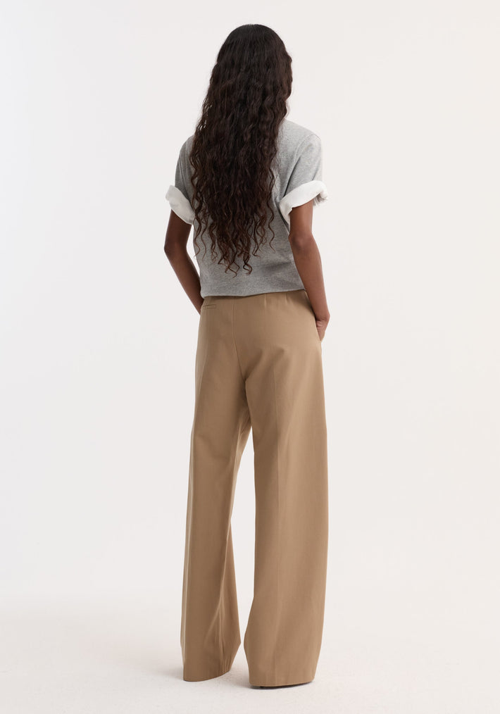 Person in heather-gray top and Classic baggy chino | beige, with hands in pockets, showcasing wide-leg fit and casual style against a plain background.