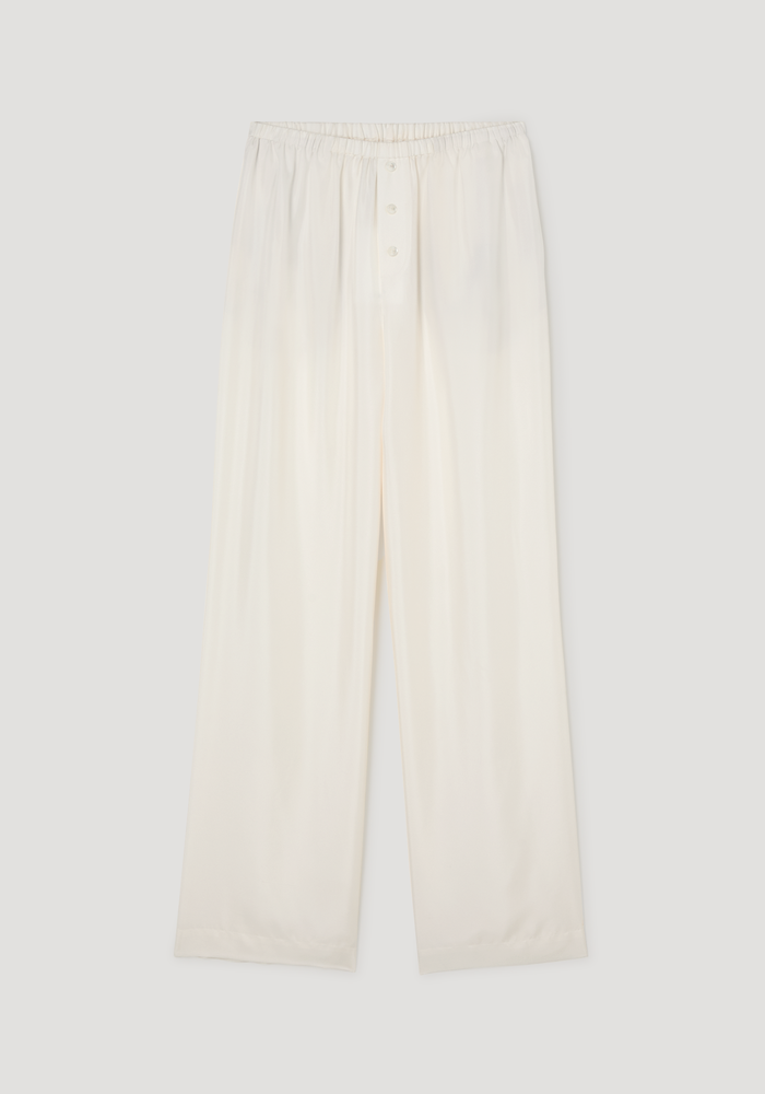 Silk pyjama trousers in a loose-leg style with an elastic waistband and three-button front, laid flat to show lightweight, silky fabric.