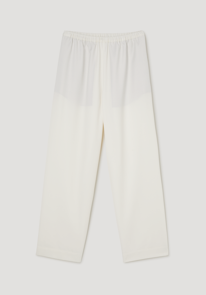 Cropped wide leg trousers in off-white, featuring an elastic waistband, ankle-length fit, and side seam pockets, laid flat against a neutral background.