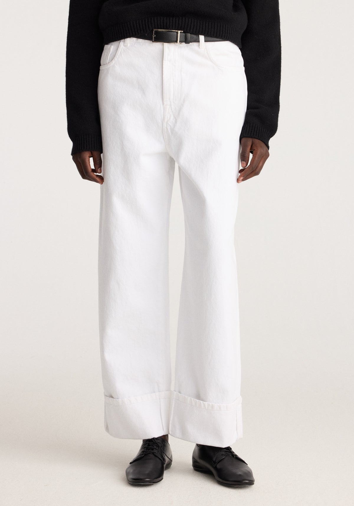 Baggy fit turn-up denim | optic white shown on a model with wide legs rolled cuffs belt loops and black shoes against a neutral studio background