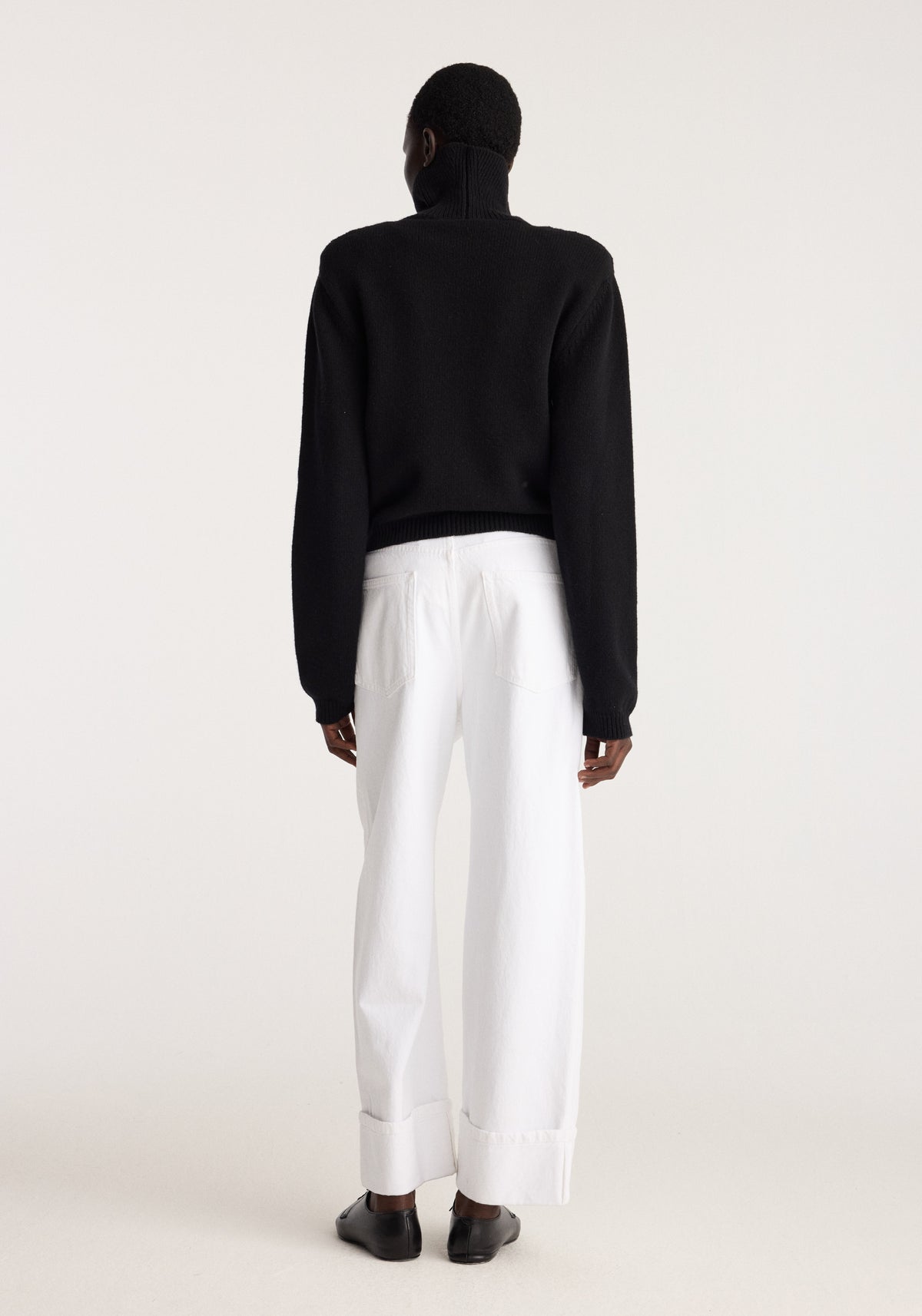 Baggy fit turn-up denim | optic white shown from the back on a model with wide legs and turn-up hems styled with a black sweater and shoes