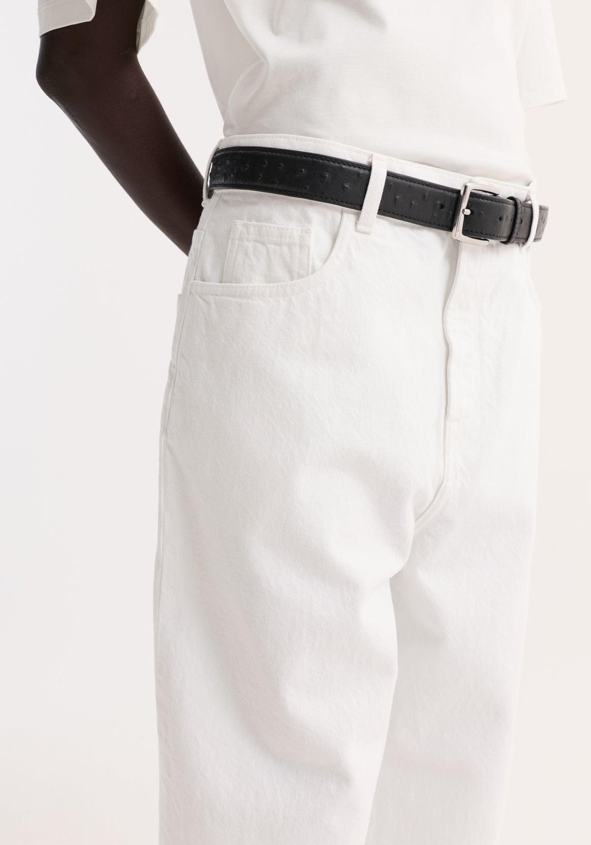 Baggy fit turn-up denim in optic white, showcasing a high-waisted, low-rise design with a black leather belt and silver buckle.
