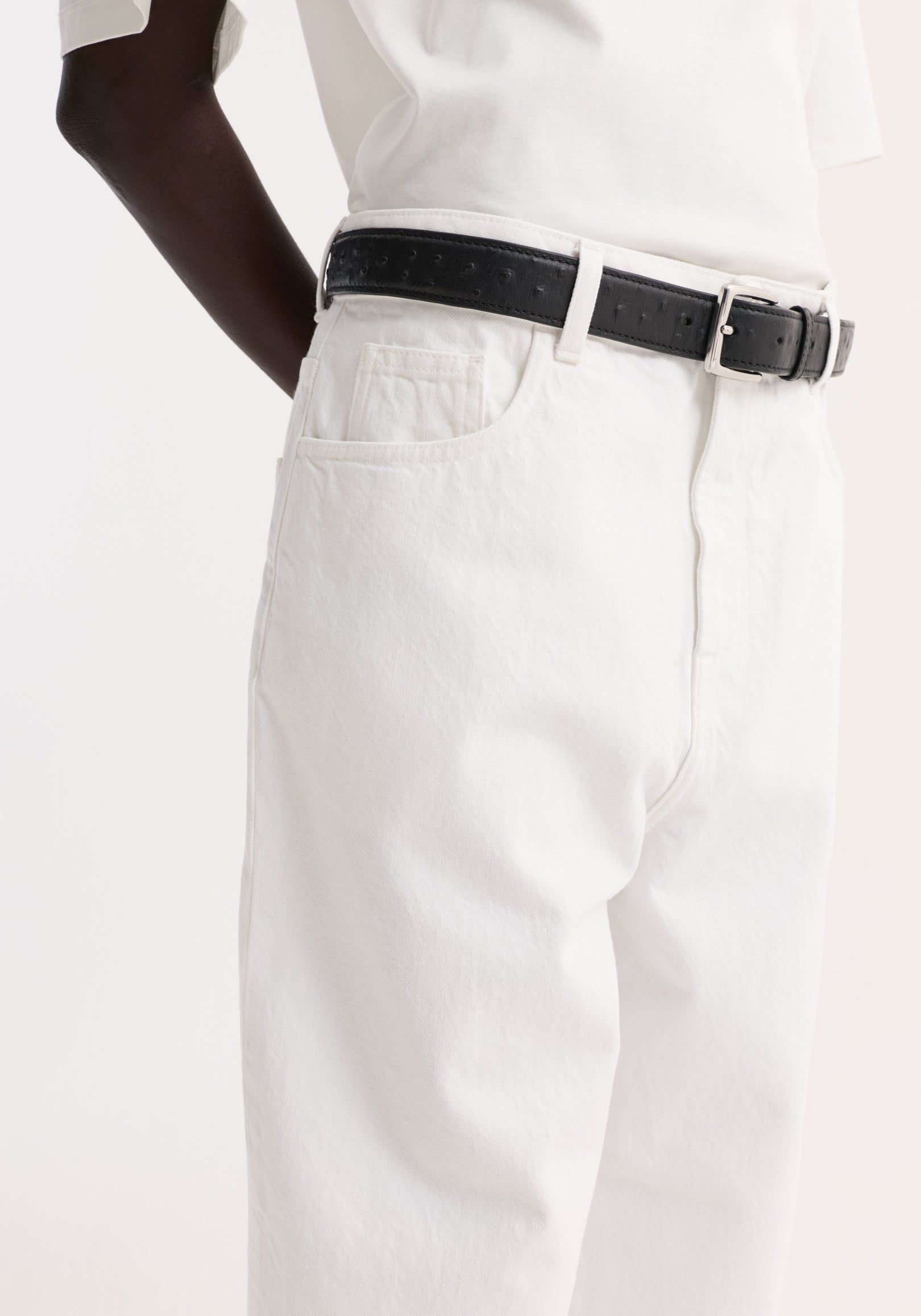 Baggy fit turn-up denim in optic white, showcasing a high-waisted, low-rise design with a black leather belt and silver buckle.