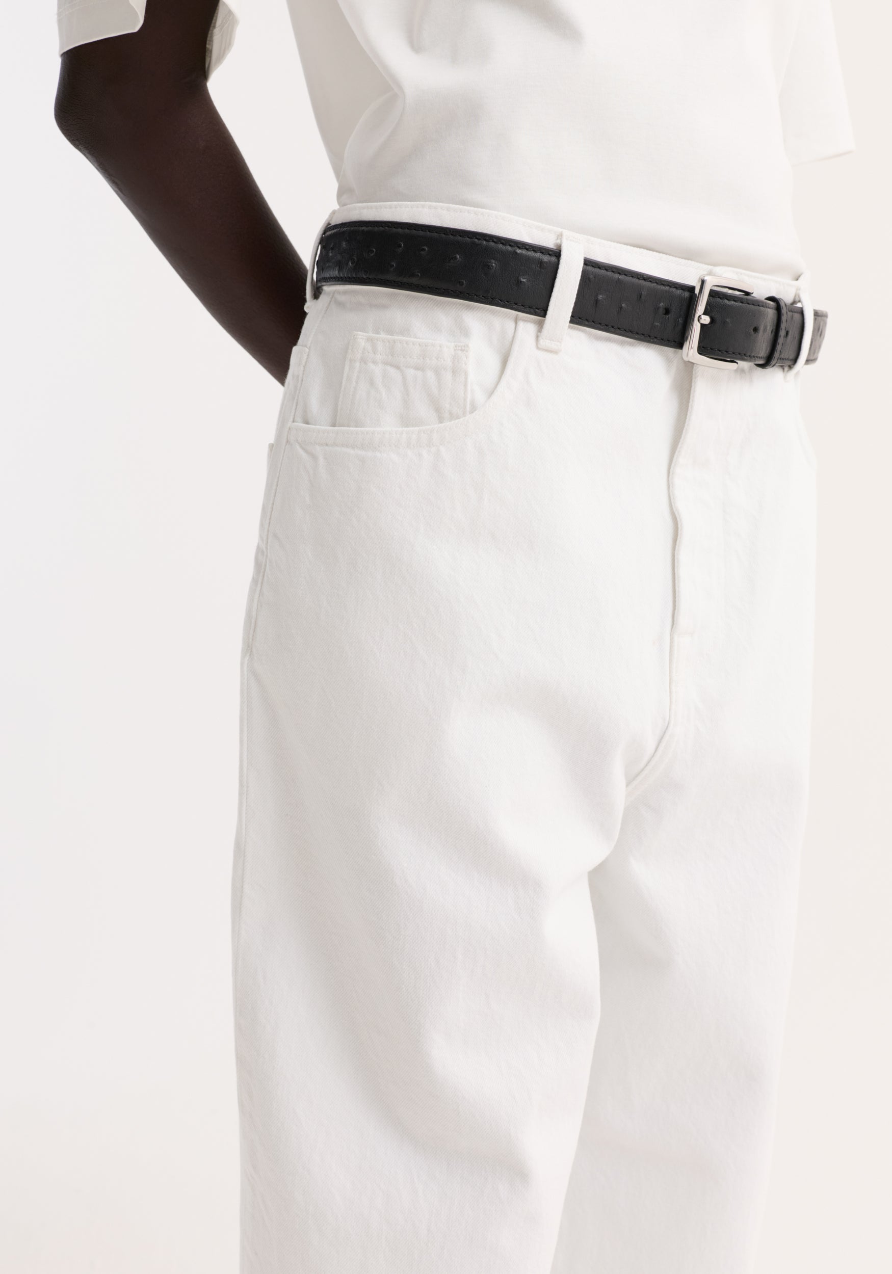 Baggy fit turn-up denim in optic white, showcasing a high-waisted, low-rise design with a black leather belt and silver buckle.