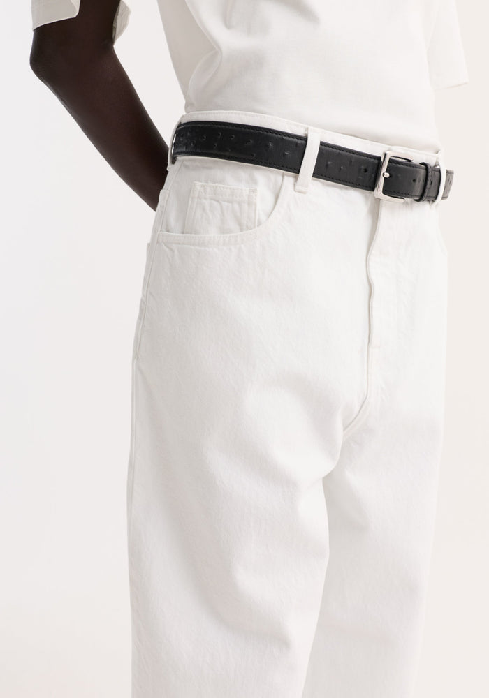 Baggy fit turn-up denim in optic white, featuring a high-waist look with a black leather belt, showcasing its wide-leg, turned-up hem design.