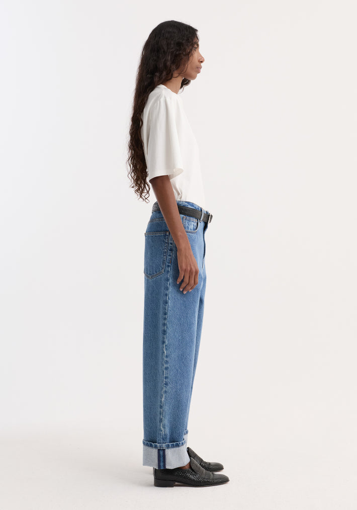 Turn-up baggy denim | heritage blue, featuring a side-profile view with a loose-fit, low-rise, wide-leg design, turned-up cuffs, and a black belt accent.