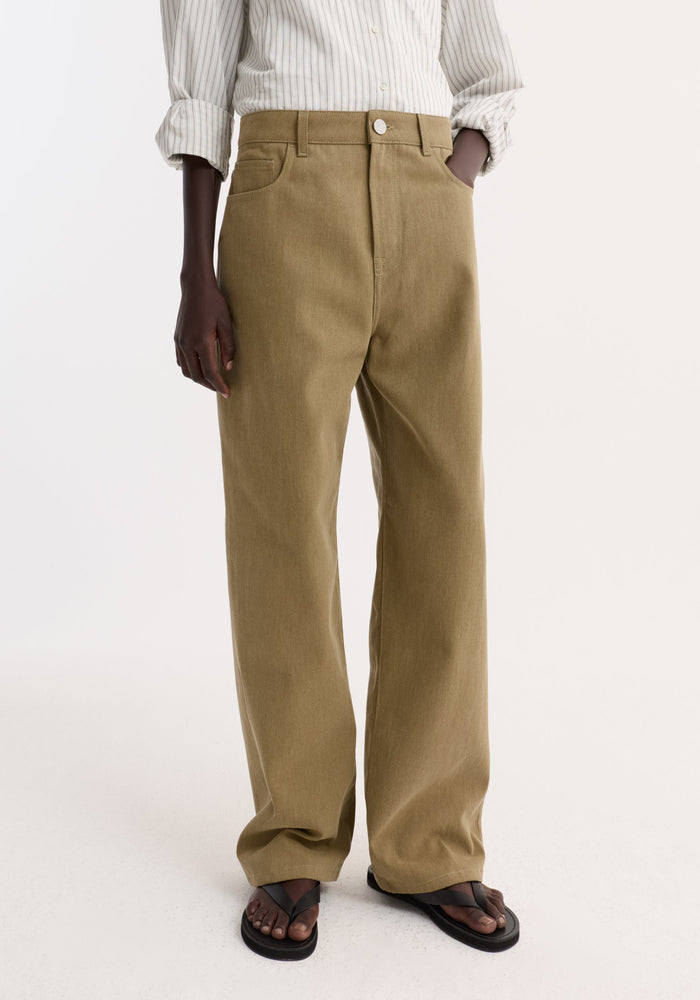 Baggy fit denim | sage trousers with a low-waist, wide-leg design, subtle tone variations, and a branded button, paired with black thong sandals.