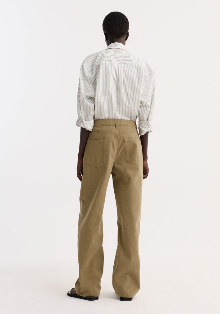 Person wearing Baggy fit denim | sage, showcasing low-waist, wide-leg trousers with delavé-finished fabric, rolled-up sleeves, and black sandals, creating a clean, minimalist look.