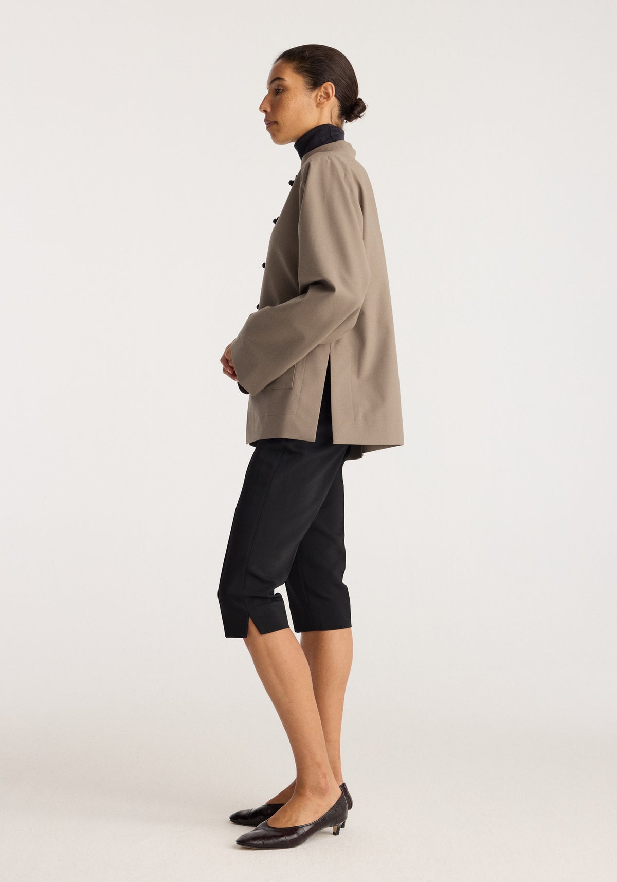 Capri | black black cropped trousers styled with a taupe jacket and pointed black heels on a model in side profile indoors