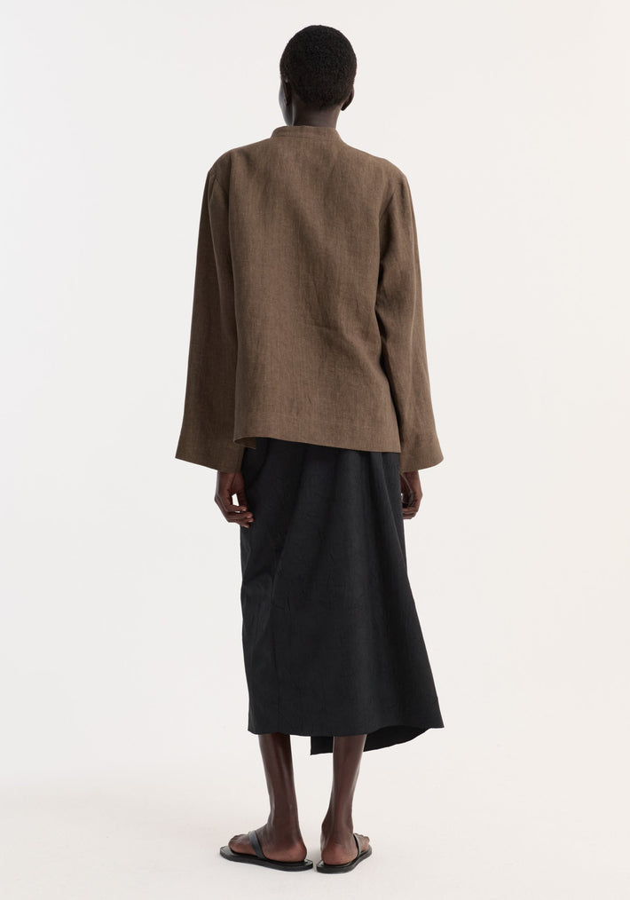 Person wearing a Sarong textured skirt | black, showcasing the back view with a knot detail and gathered fabric, paired with slide sandals.