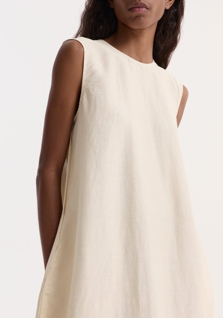 Hourglass linen silk dress | butter: A person wears a sleeveless, floor-length A-line dress with a sculptural shape, crafted from a textured linen-silk blend.