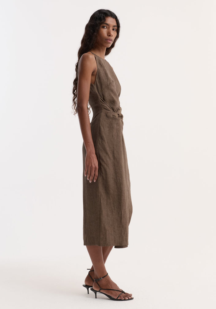 Model wearing Sarong dress | brown melange, sleeveless, calf-length, with high neck and back, featuring a waist knot. Paired with black strappy heeled sandals.