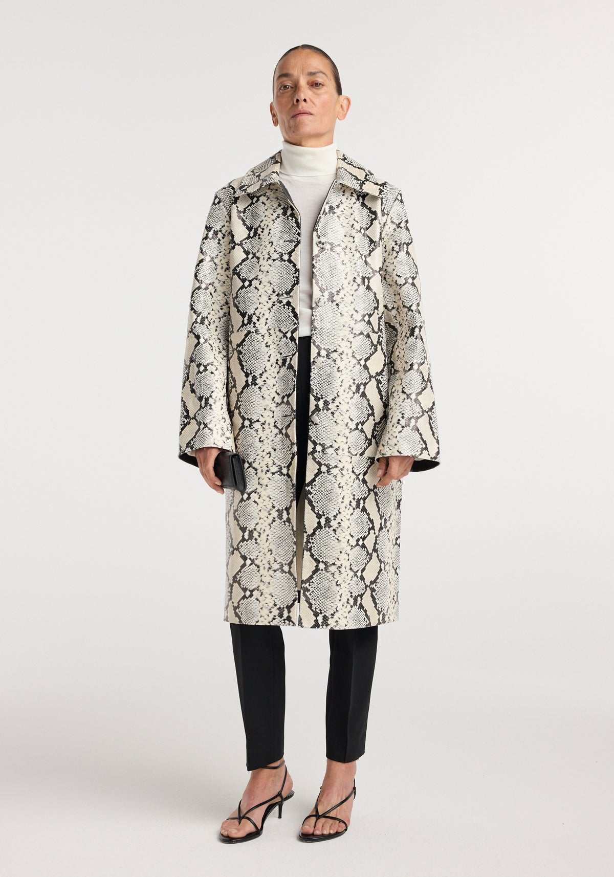 Snakeskin leather coat | snakeskin featuring a cream and black snakeskin pattern with notched lapels worn over a white turtleneck and black trousers