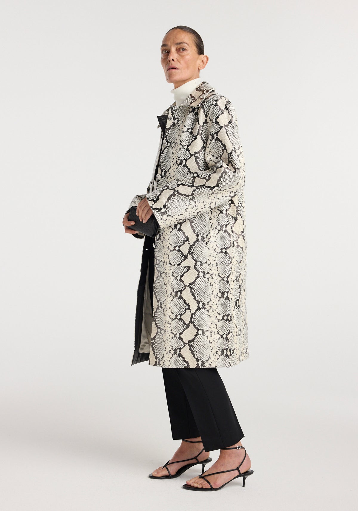 Snakeskin leather coat | snakeskin in a grey snakeskin pattern worn by a model with black trousers and strappy heels against a light studio background
