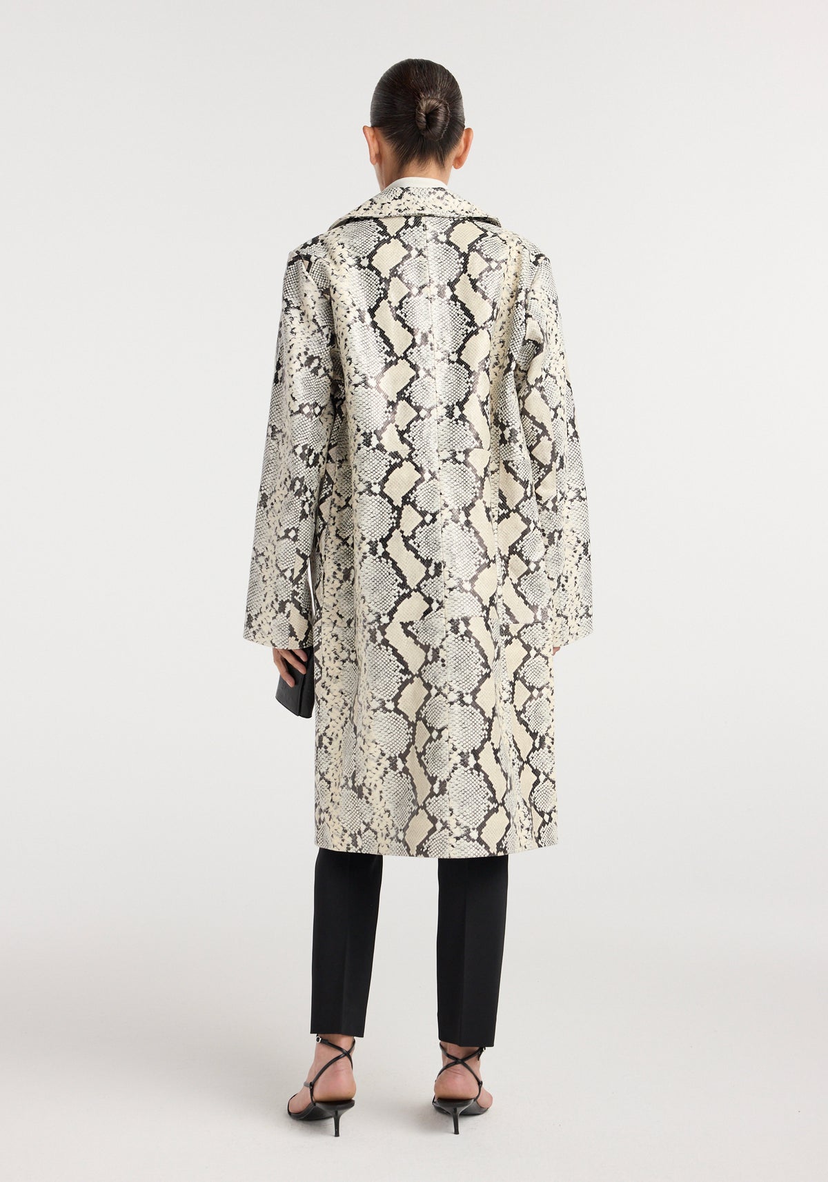 Snakeskin leather coat | snakeskin shown from the back on a model in black trousers and strappy heels with a long beige and gray snakeskin pattern