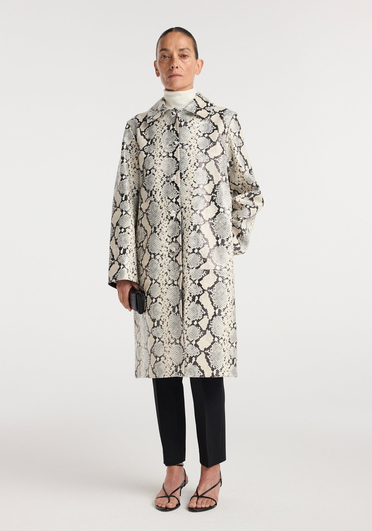 Snakeskin leather coat | snakeskin worn by a model, featuring a gray and black snakeskin pattern, high collar, long sleeves, and straight knee length fit.