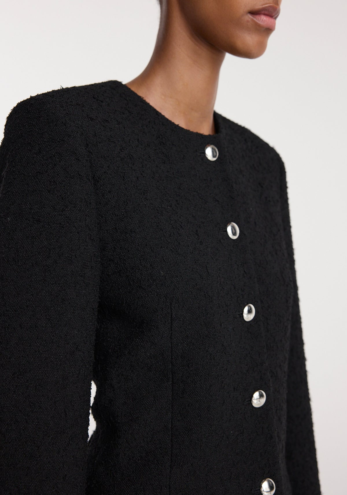 Bouclé shaped blazer | black in textured black fabric with a collarless neckline long sleeves and four silver tone front buttons