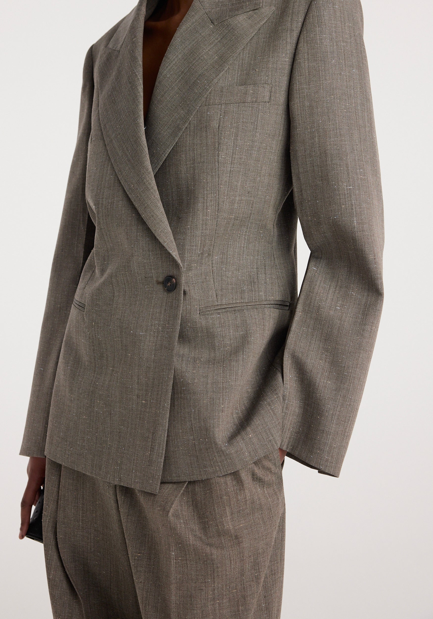 Close-up of a tailored hourglass shaped blazer | earth slub in a textured earth-tone fabric with a single button closure and structured lapels.