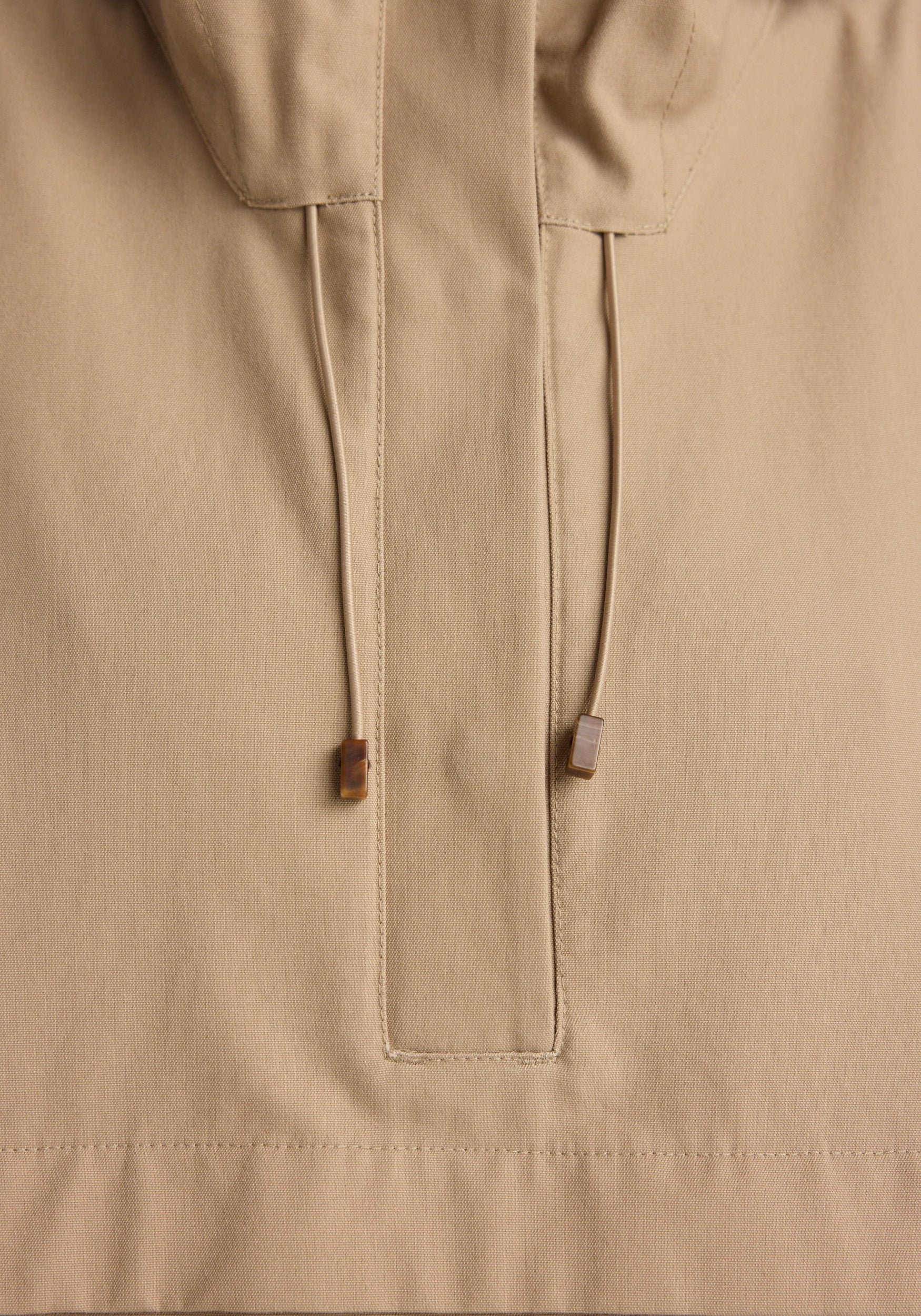 Close-up detail of the drawstrings and front placket on a beige Hooded anorak | beige made from smooth fabric.