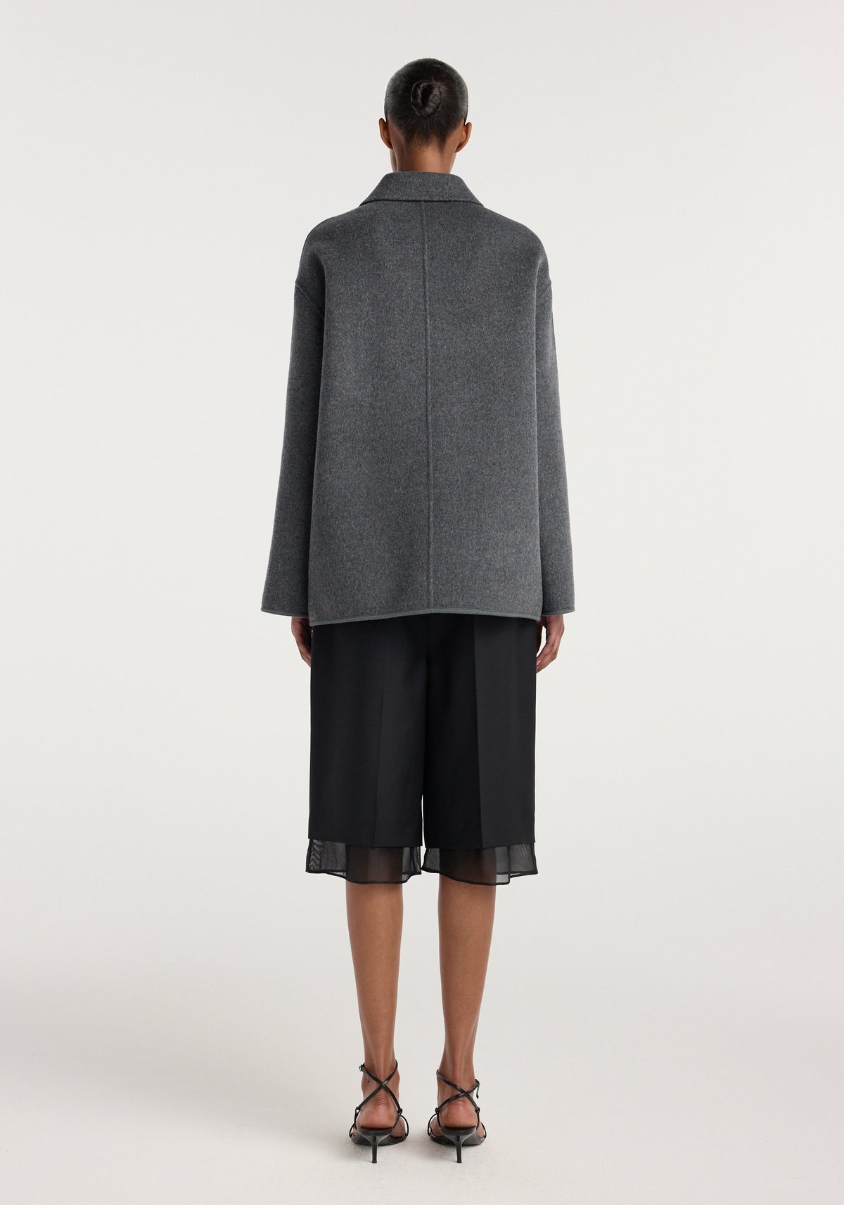 Double-faced wool pankou closure jacket | dark grey melange shown from the back on a model with black wide leg shorts and strappy heels