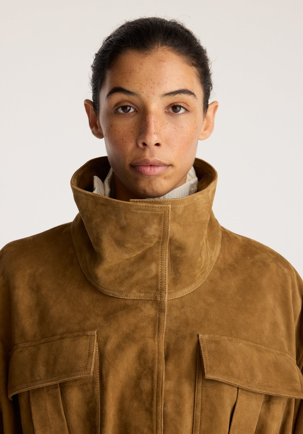 Sculptural suede jacket | sage with a high stand collar front zip closure and oversized flap pockets shown in a warm brown suede finish