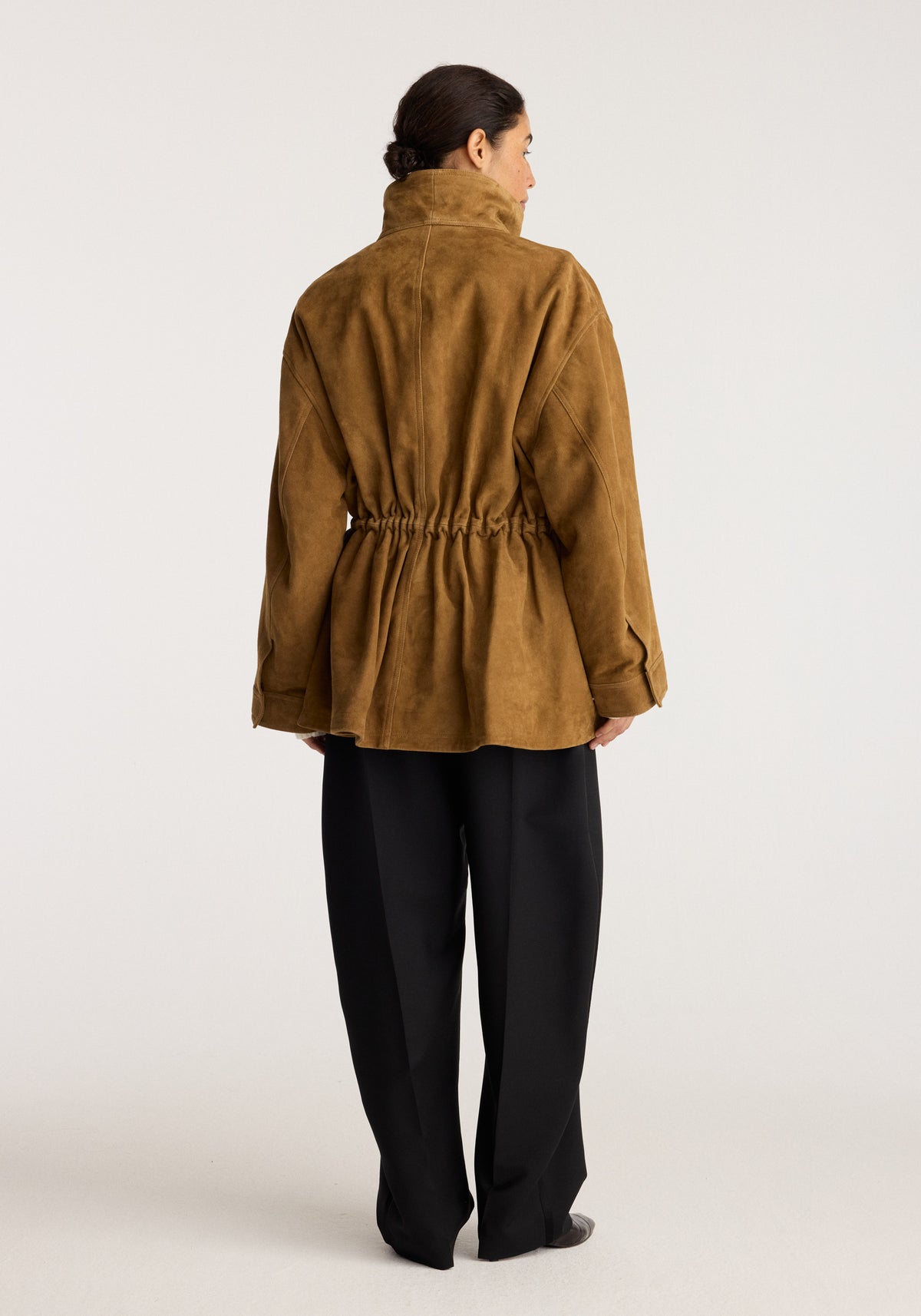 Sculptural suede jacket | sage shown from the back on a model with a gathered waist drawstring and relaxed fit with long sleeves